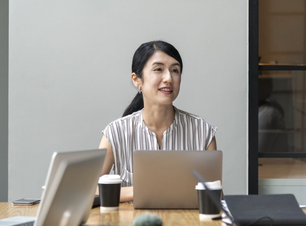 Local business woman sits at meeting room table in front of laptop